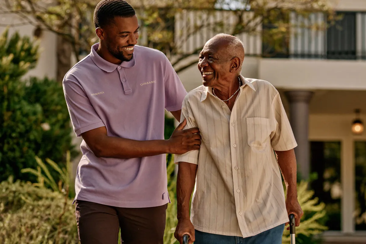 A Faithful Servants caregiver supporting a cheerful elderly client on a walk outdoors